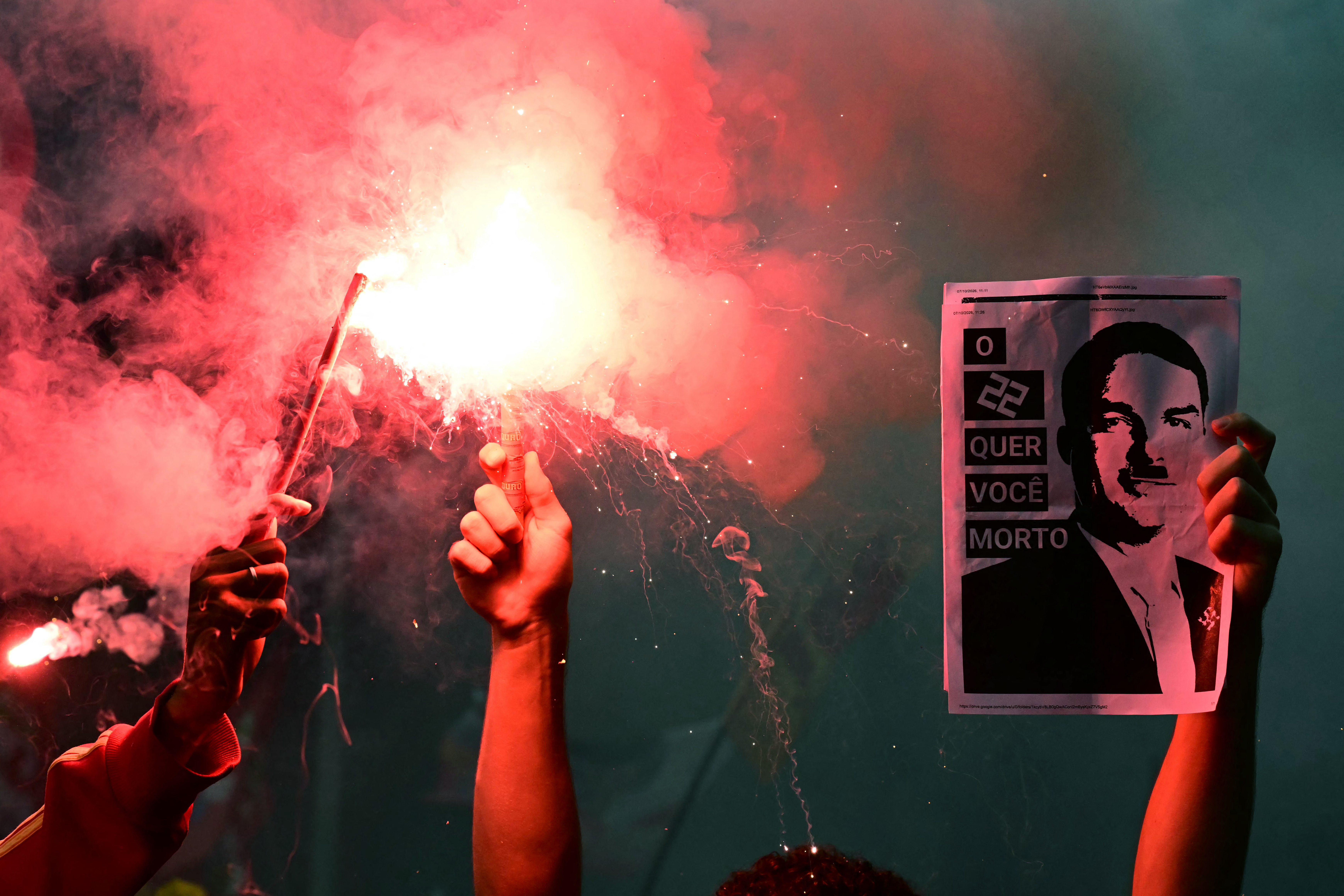 Students backing Brazil's President and presidential candidate Luiz Inacio Lula da Silva for the runoff election light flares while holding an image of right-wing candidate Flavio Bolsonaro personified as Adolf Hitler, during a march against the far right, in Rio de Janeiro, Brazil on October 7, 2026. Lula da Silva, who has risen from the political ashes several times, is heading to a runoff election against right-wing senator Flavio Bolsonaro on October 25, after a shock second-place finish in the first-round vote. (Photo by Pablo PORCIUNCULA / AFP)