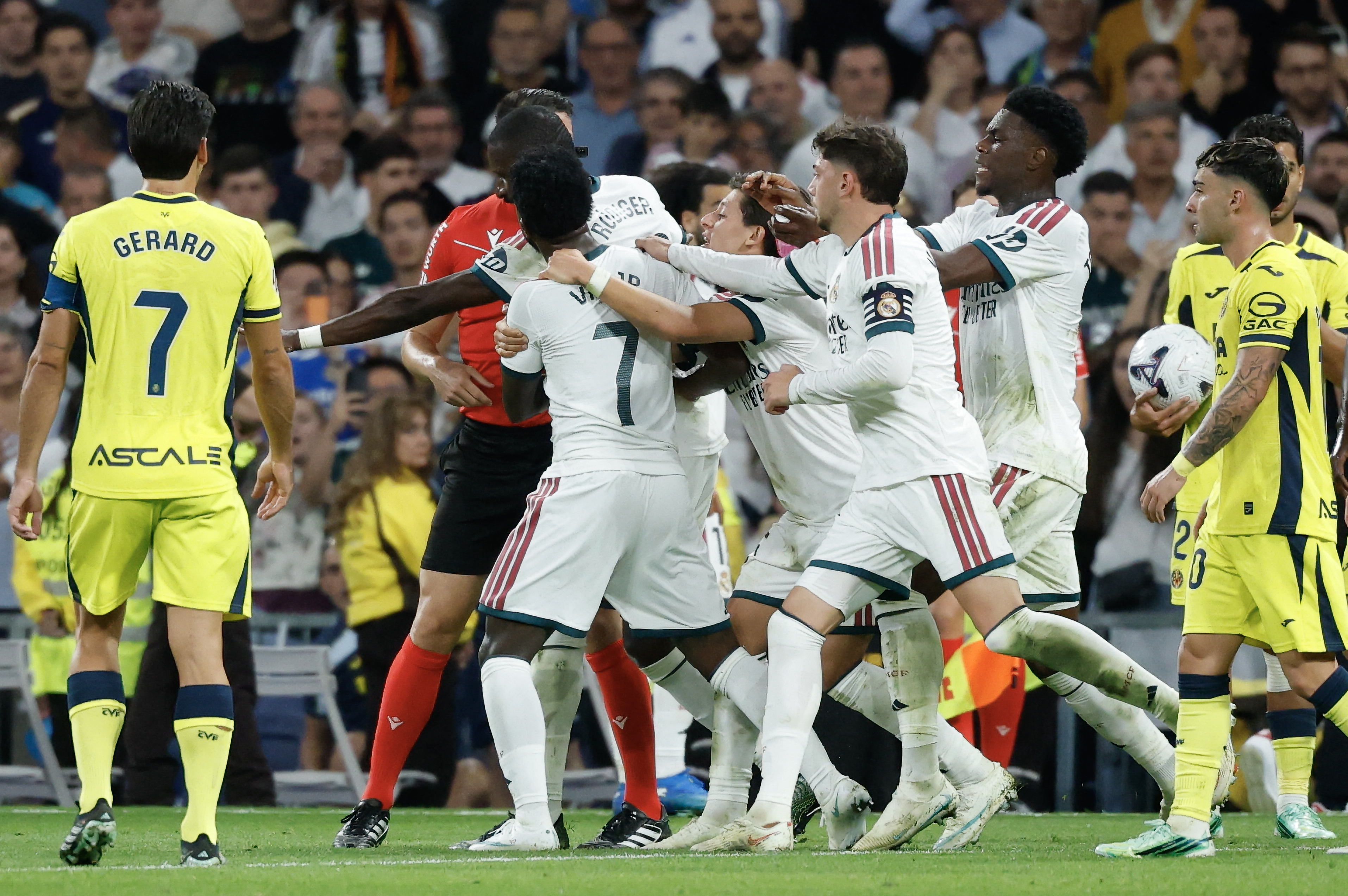 Real Madrid's Brazilian forward #07 Vinicius Junior (C) is restrained by teammates as he argues with referee Isidro Escuderos after receiving a red card during the Spanish league football match between Real Madrid CF and Villarreal CF at the Santiago Bernabeu Stadium in Madrid on October 10, 2026. (Photo by Oscar DEL POZO / AFP)
