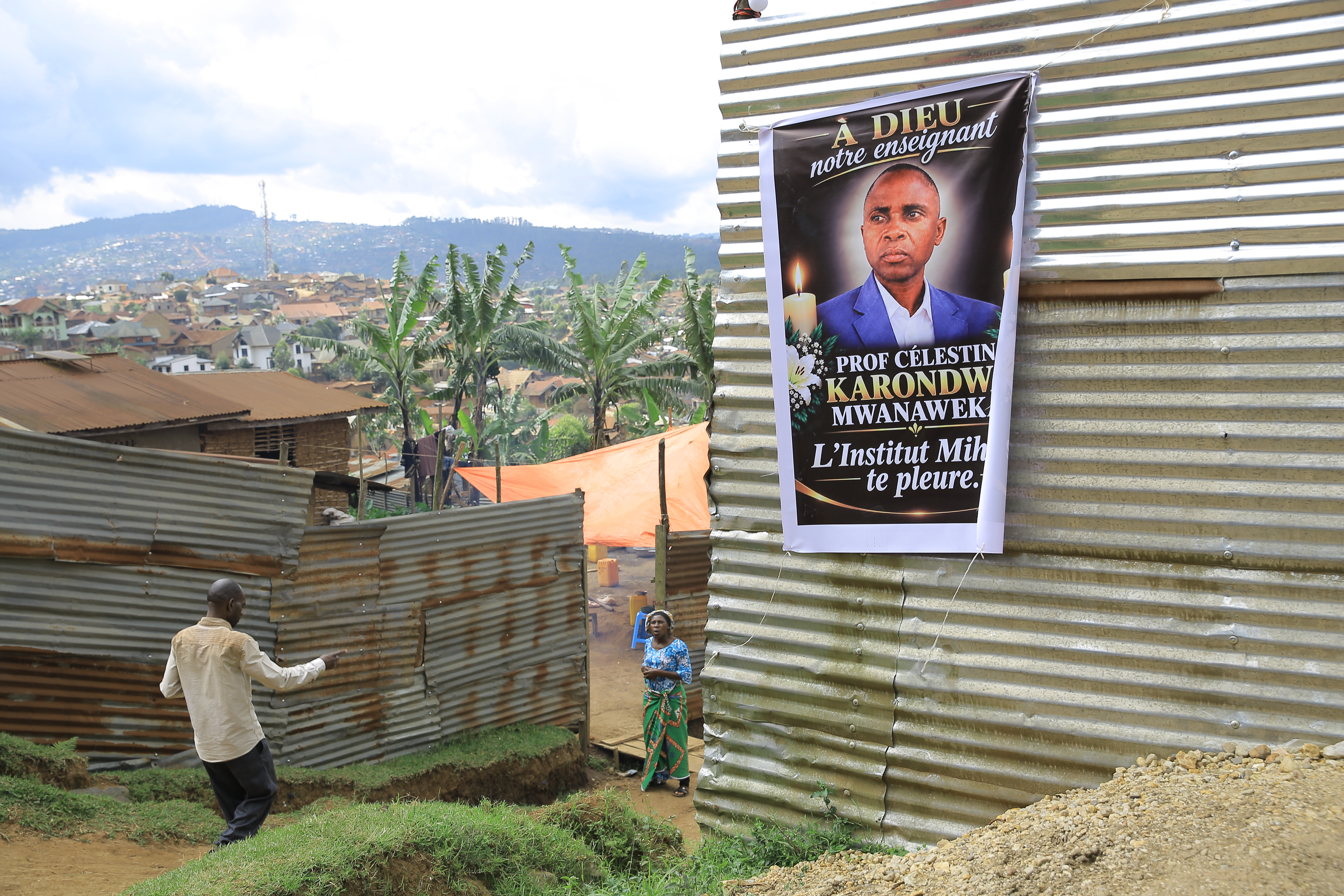 People walk past a banner with a photo of Marie-Celestin Karondwa, a local official who was beaten to death after publicly defending the government's response to Ebola, in Butembo, Congo, Wednesday, September 30, 2026 [Sebastien Kitsa Musayi/AP]
