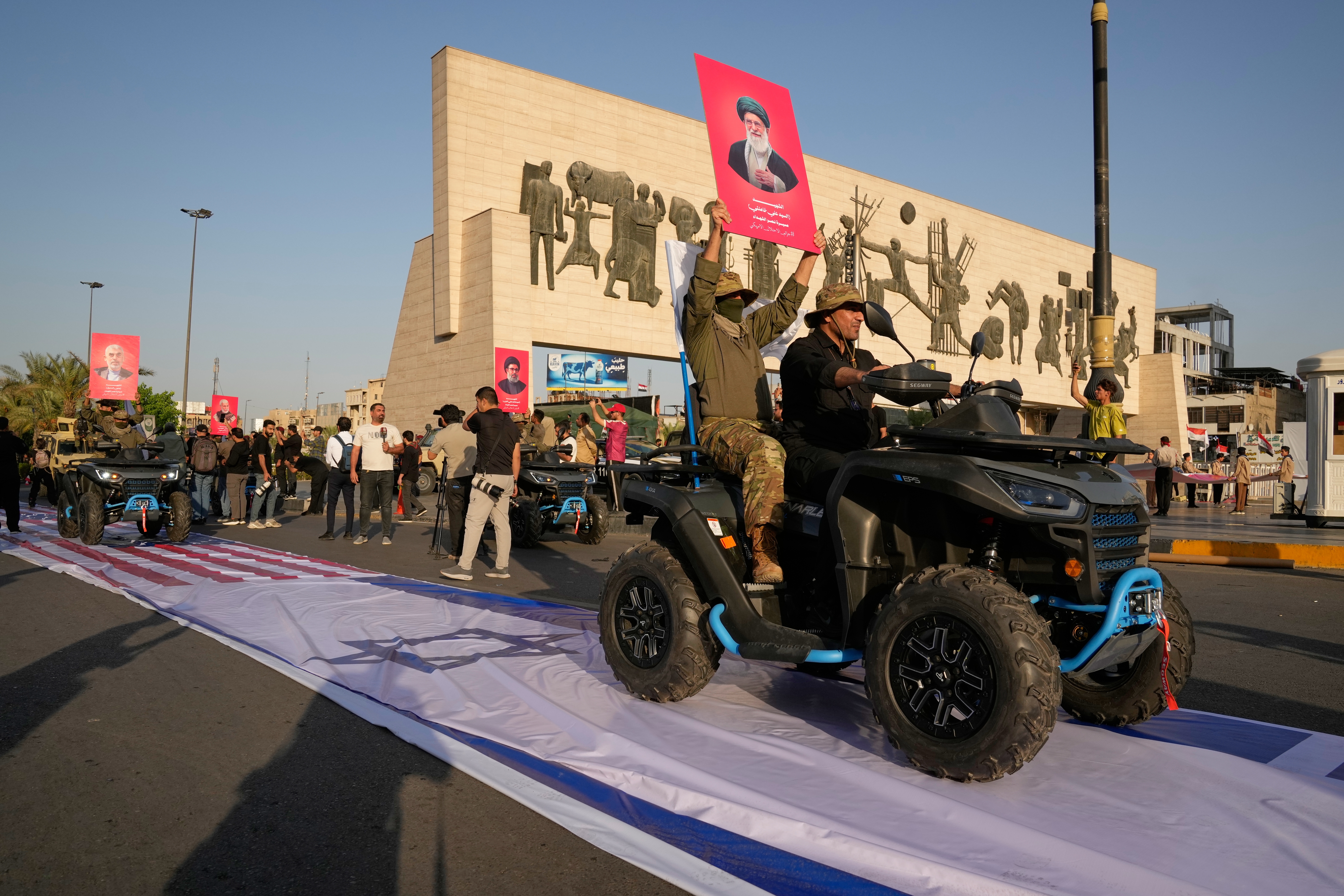 Members of Iraq's Iran-allied Popular Mobilization Forces ride over US and Israeli flags during a celebration inTahrir Square in Baghdad, Iraq, Thursday, Oct. 1, 2026 [Hadi Mizban/AP]