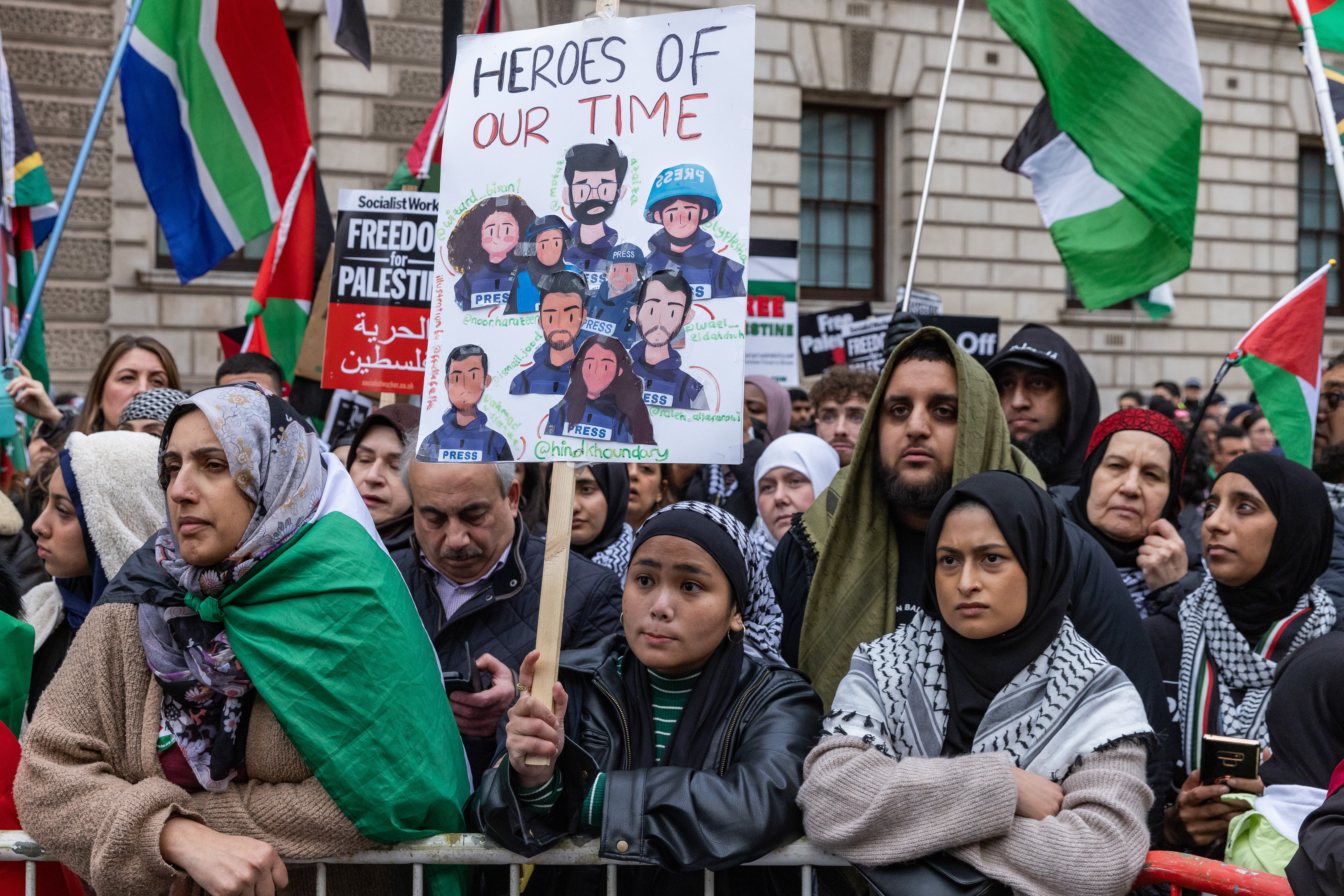 A pro-Palestinian protester holds a handmade placard paying tribute to Palestinian journalists