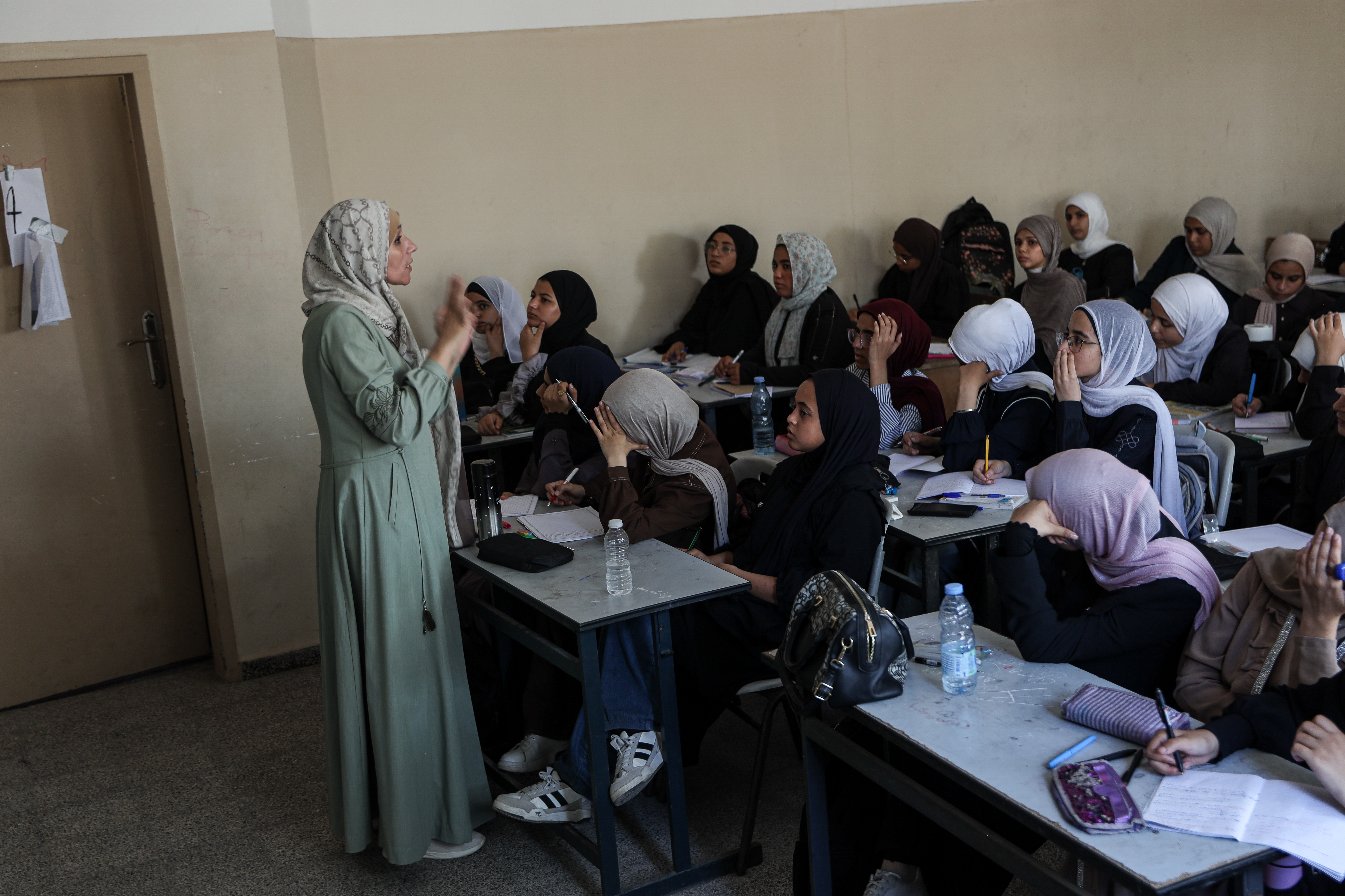 Maha Taha with her pupils at Muscat Secondary School, where she now teaches classes of 45 girls. After years of war, hunger and displacement, she says she has become less concerned with strict rules and more attentive to the difficulties her students face outside the classroom