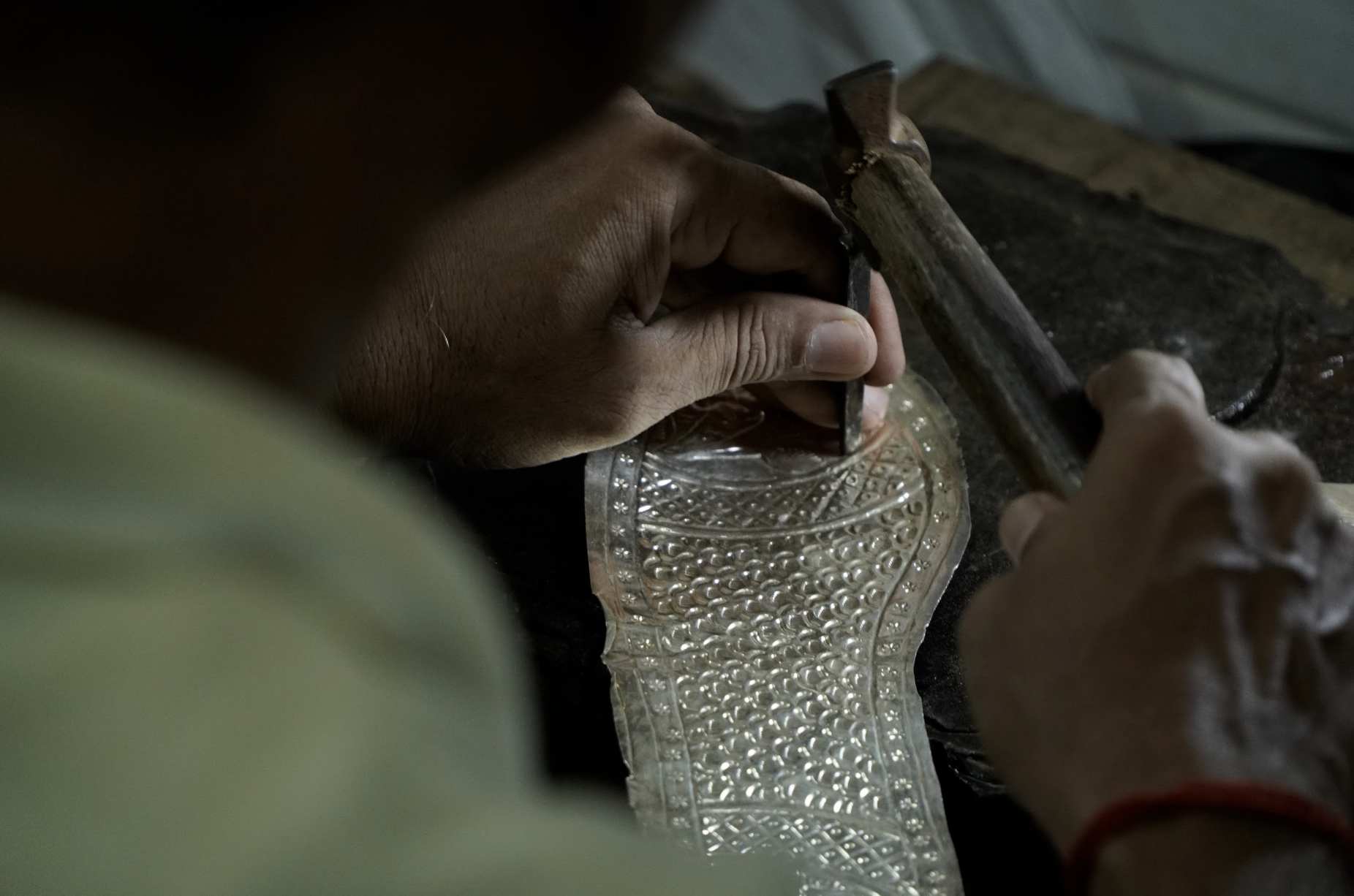 A craftsman uses a hammer and kalam, the two most important tools for making nagras, as he works on the silver [Aatif Ammad/Al Jazeera]