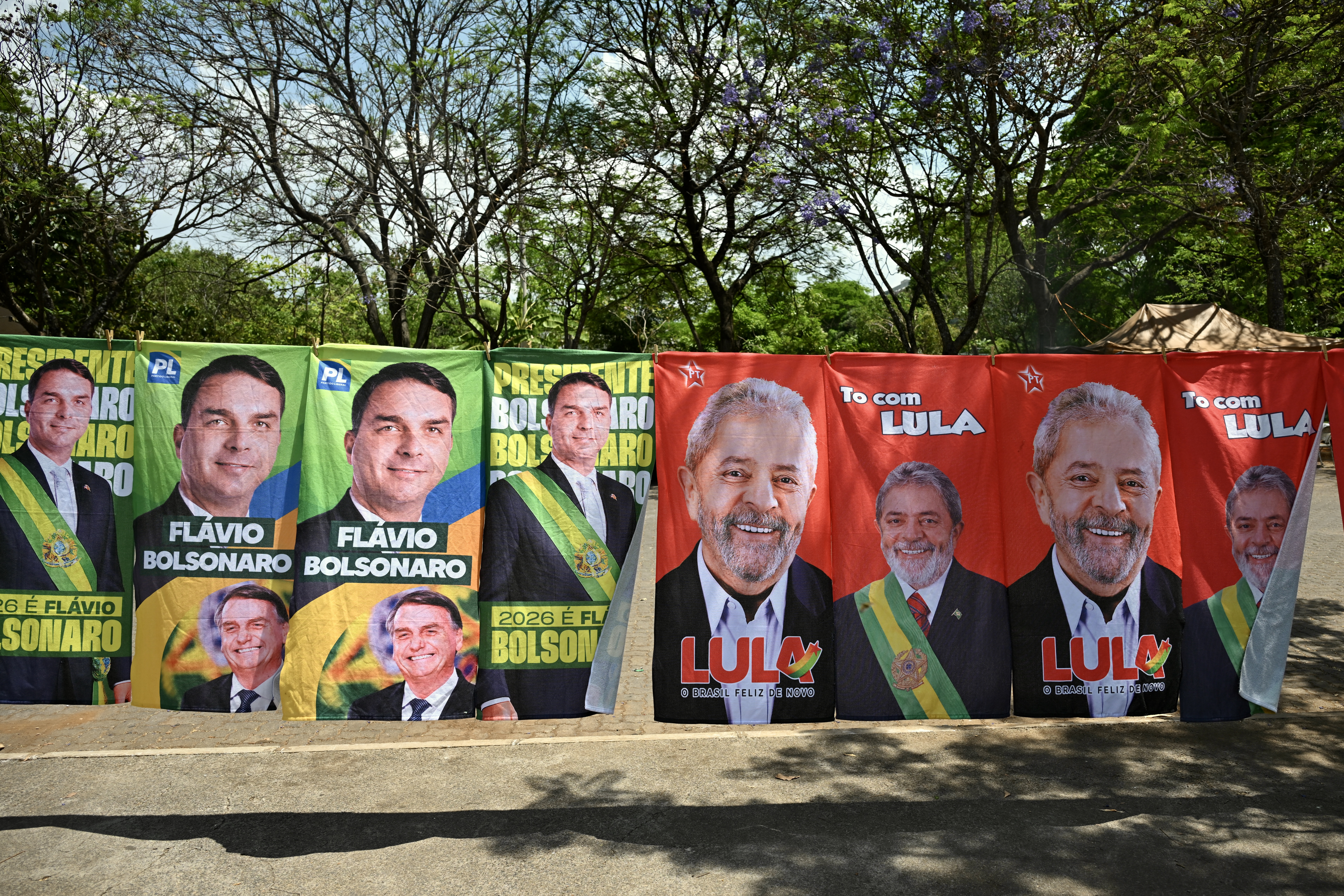 Flags and towels bearing the images of Brazil's President and presidential candidate Luiz Inacio Lula da Silva and right-wing senator and presidential candidate Flavio Bolsonaro are displayed for sale on a street in Brasilia on September 30, 2026.