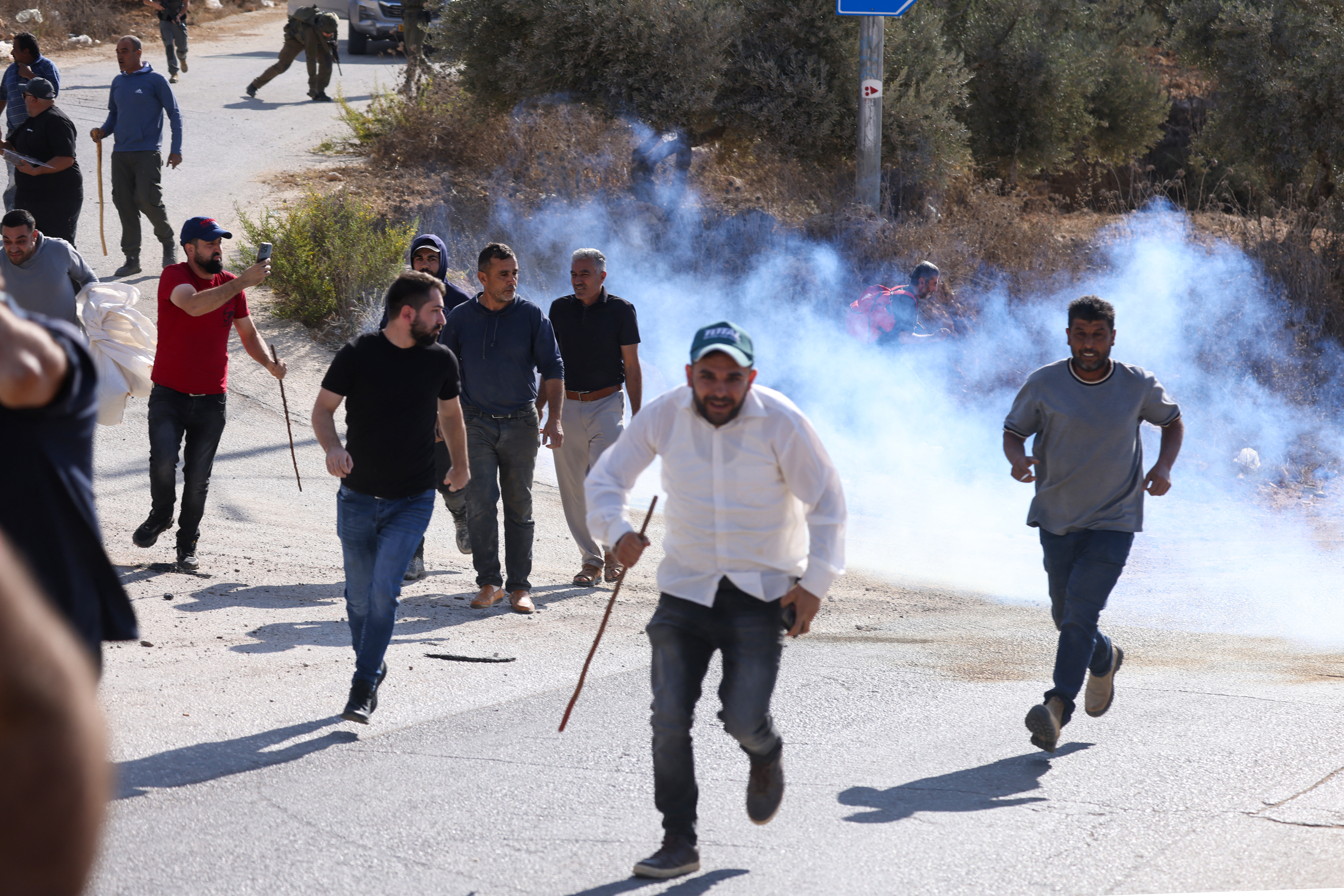 Palestinians run for cover after reportedly being attacked by Israeli settlers and soldiers while picking olives in the village of Beita, south of Nablus, in the occupied West Bank on October 2, 2026.