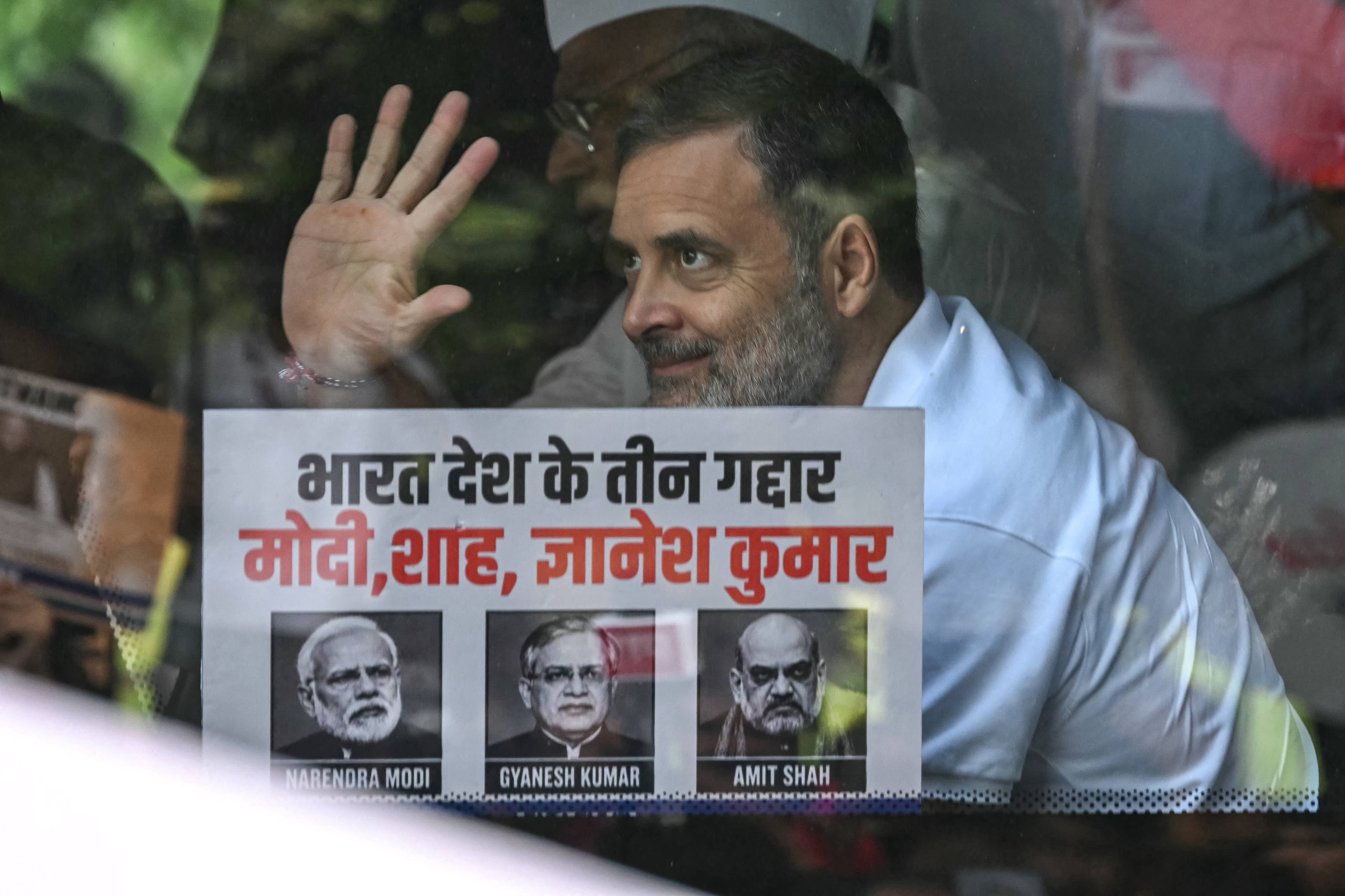 India's Congress party leader Rahul Gandhi waves from a bus to participate in a protest by the opposition alliance INDIA bloc (Indian National Developmental Inclusive Alliance) at Rajghat in New Delhi on October 8, 2026 against the country's Chief Election Commissioner Gyanesh Kumar calling for his resignation over alleged irregularities in the Special Intensive Revision (SIR) of electoral rolls.