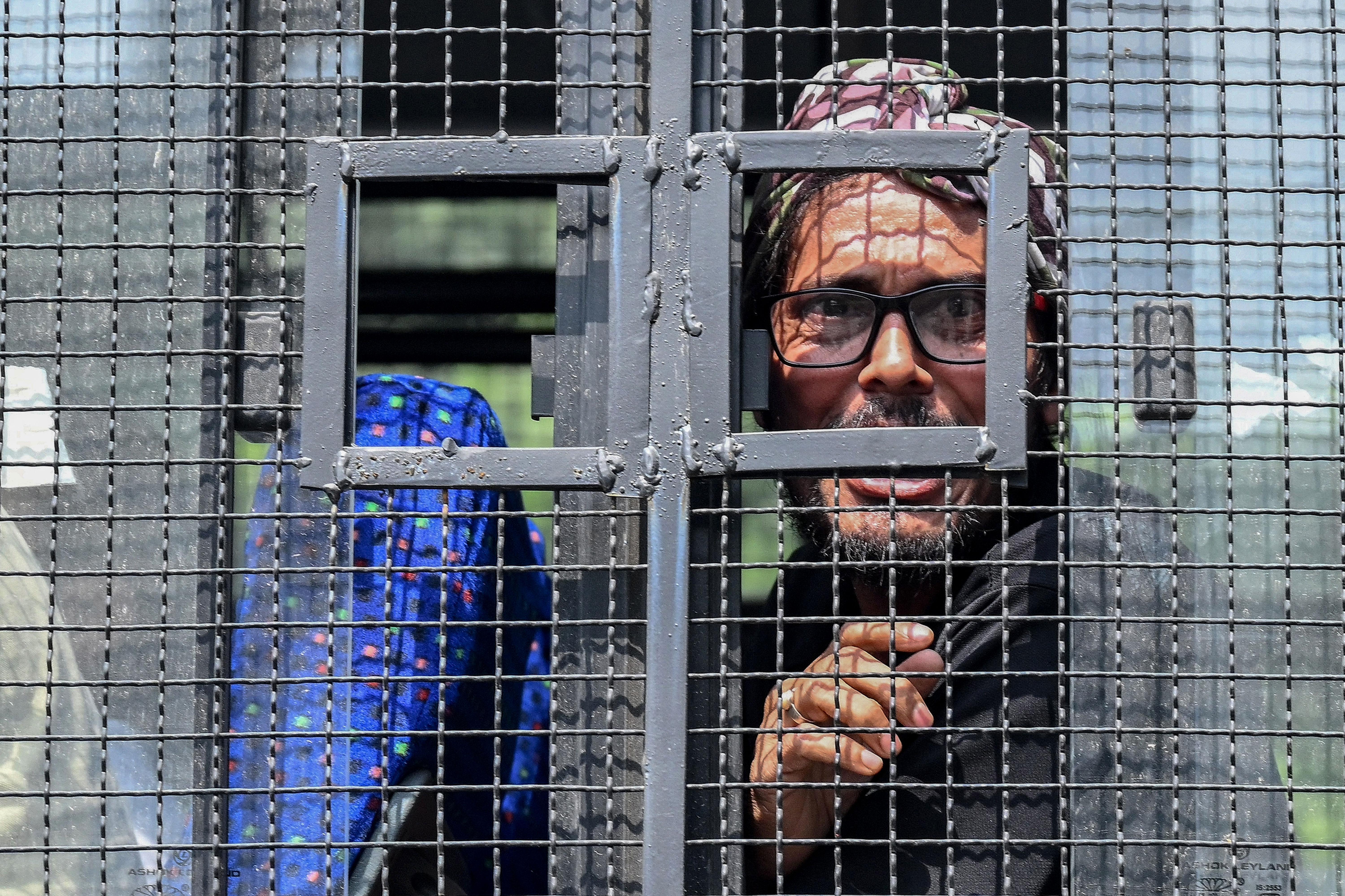A supporter of the Cockroach Janata Party (CJP) looks out from a police van after being detained by police during a protest demanding the resignation of India’s Chief Election Commissioner Gyanesh Kumar over alleged voter roll irregularities linked to the "special intensive revision" (SIR), in New Delhi on October 10, 2026.
