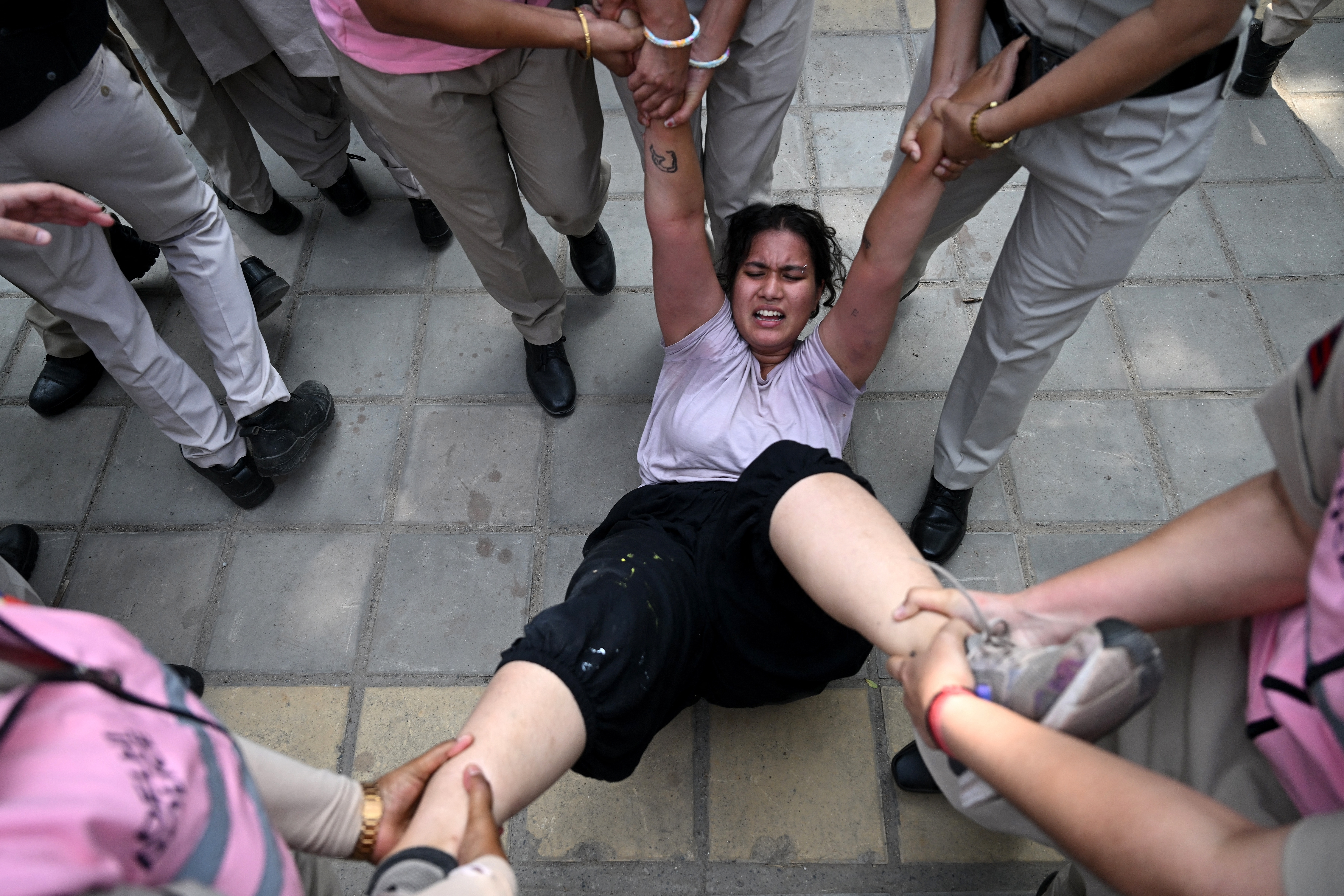 Police personnel detain a supporter of the Cockroach Janata Party (CJP) during a protest demanding the resignation of India’s Chief Election Commissioner Gyanesh Kumar over alleged voter roll irregularities linked to the "special intensive revision" (SIR), in New Delhi on October 10, 2026.