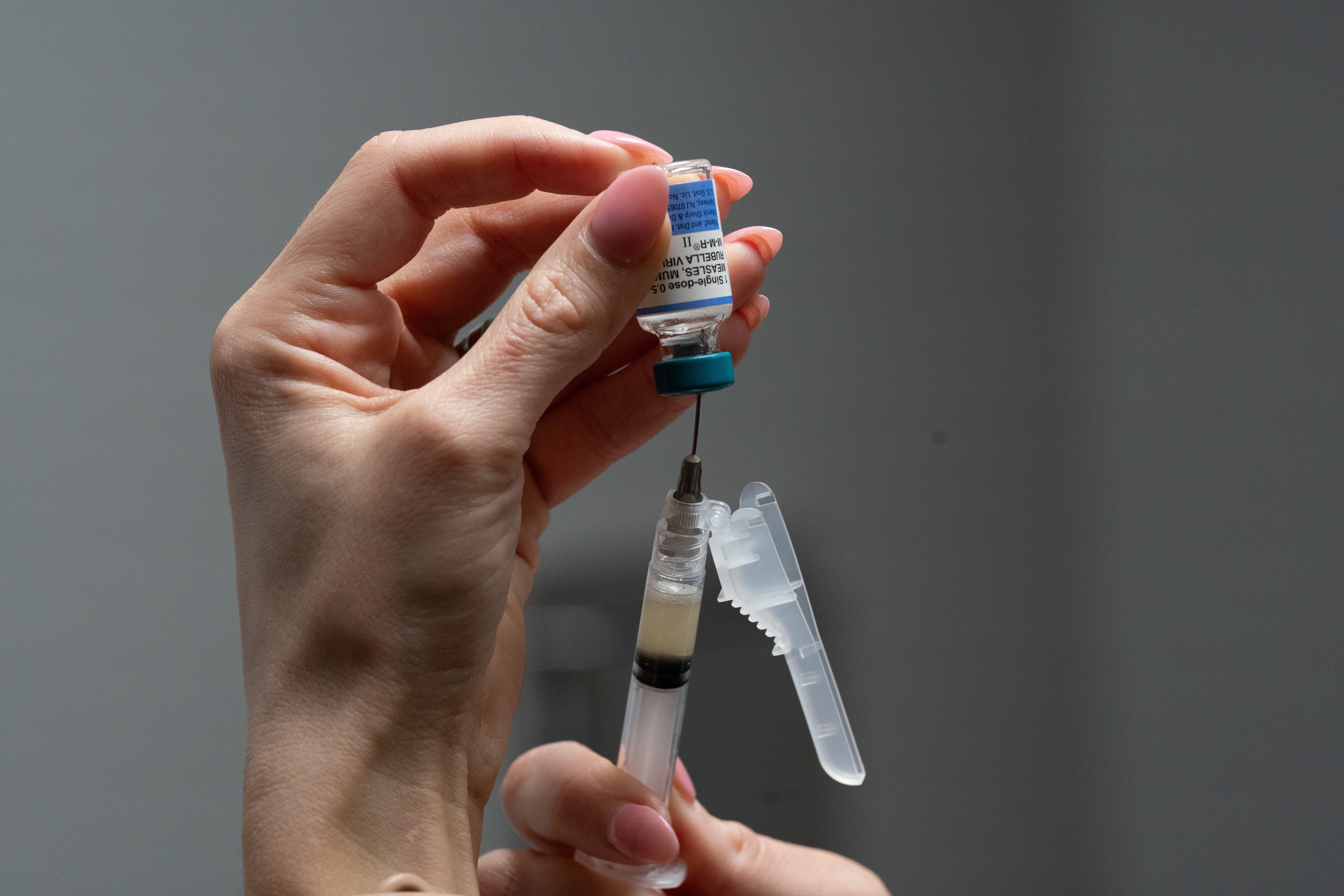 A nurse, prepares a combination measles, mumps and rubella vaccine for a patient