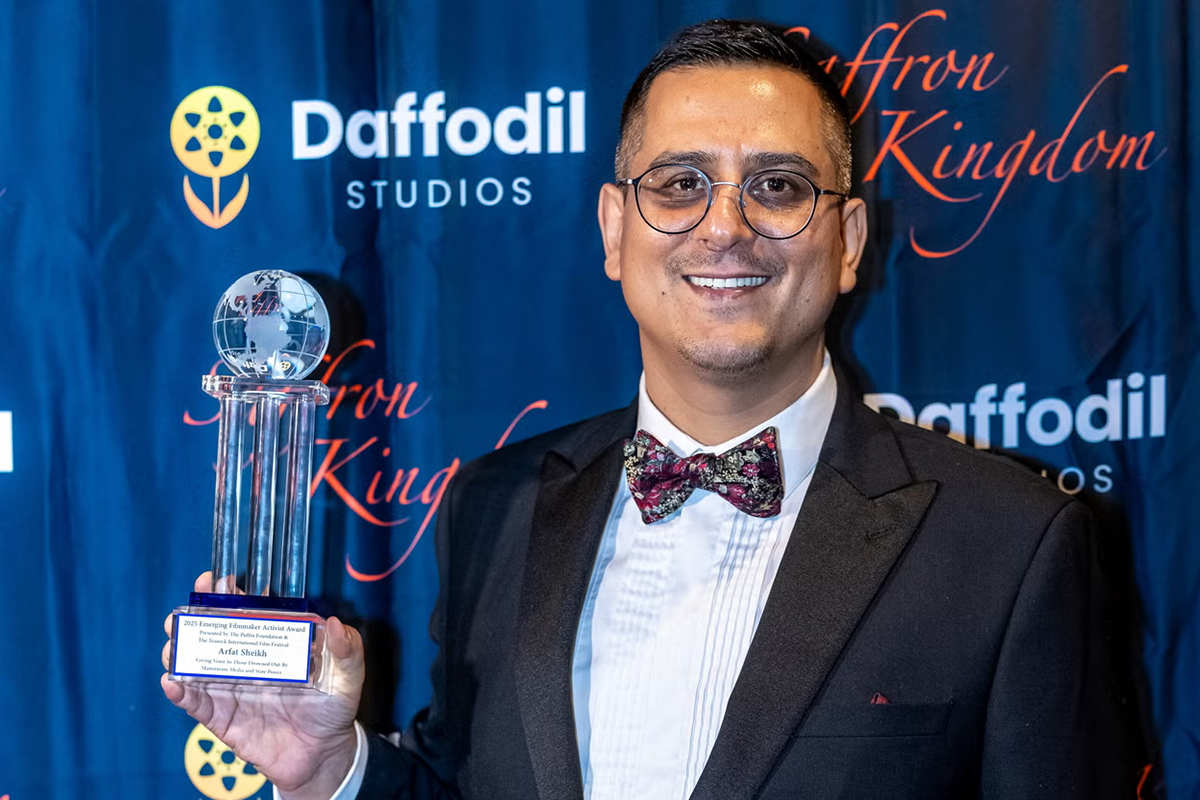 Arfat Sheikh smiles as he holds an award.