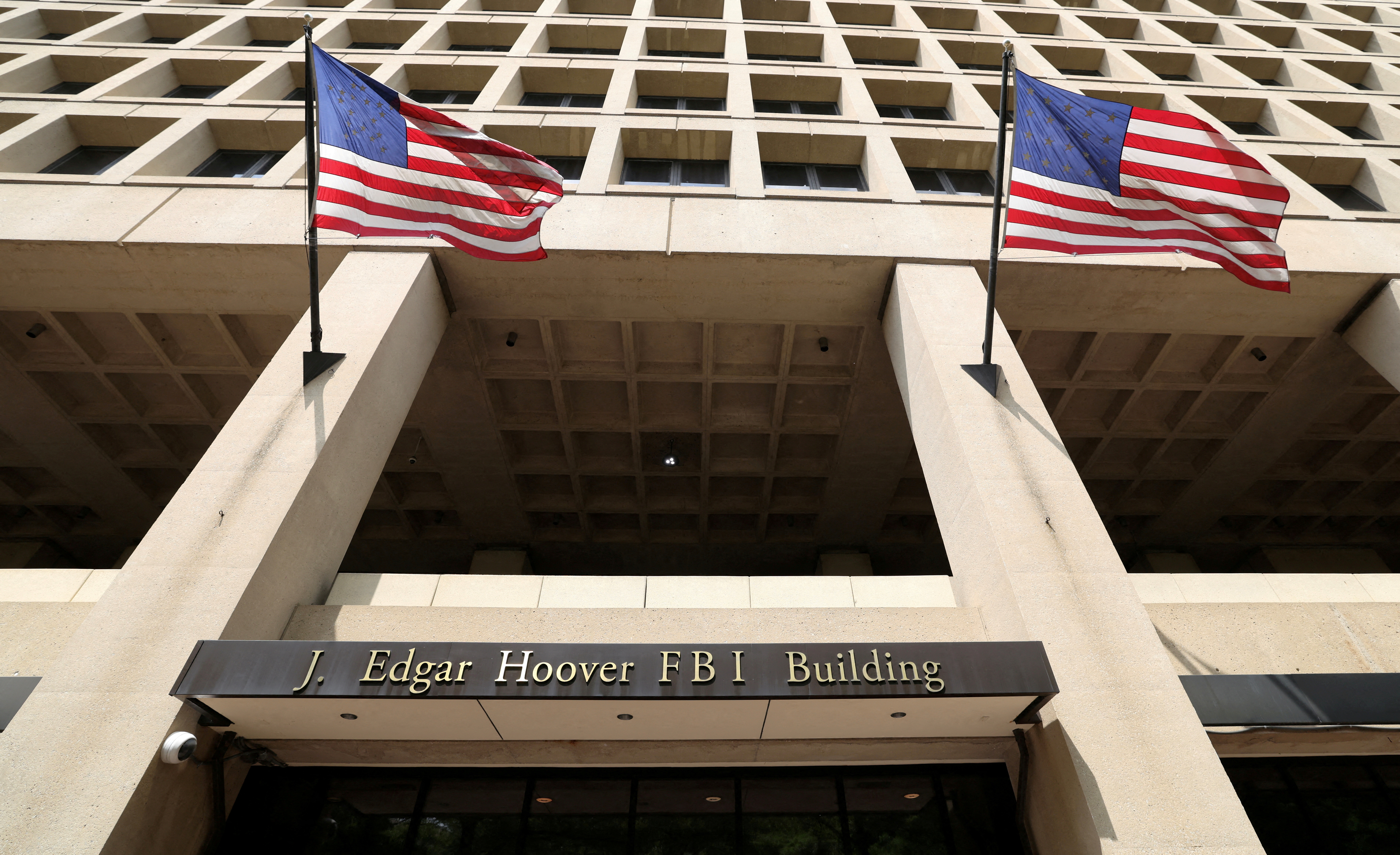 U.S. flags flutter in the wind over the entrance to the J. Edgar Hoover Building in Washington, D.C., U.S., May 16, 2025. REUTERS/Kevin Lamarque/File Photo