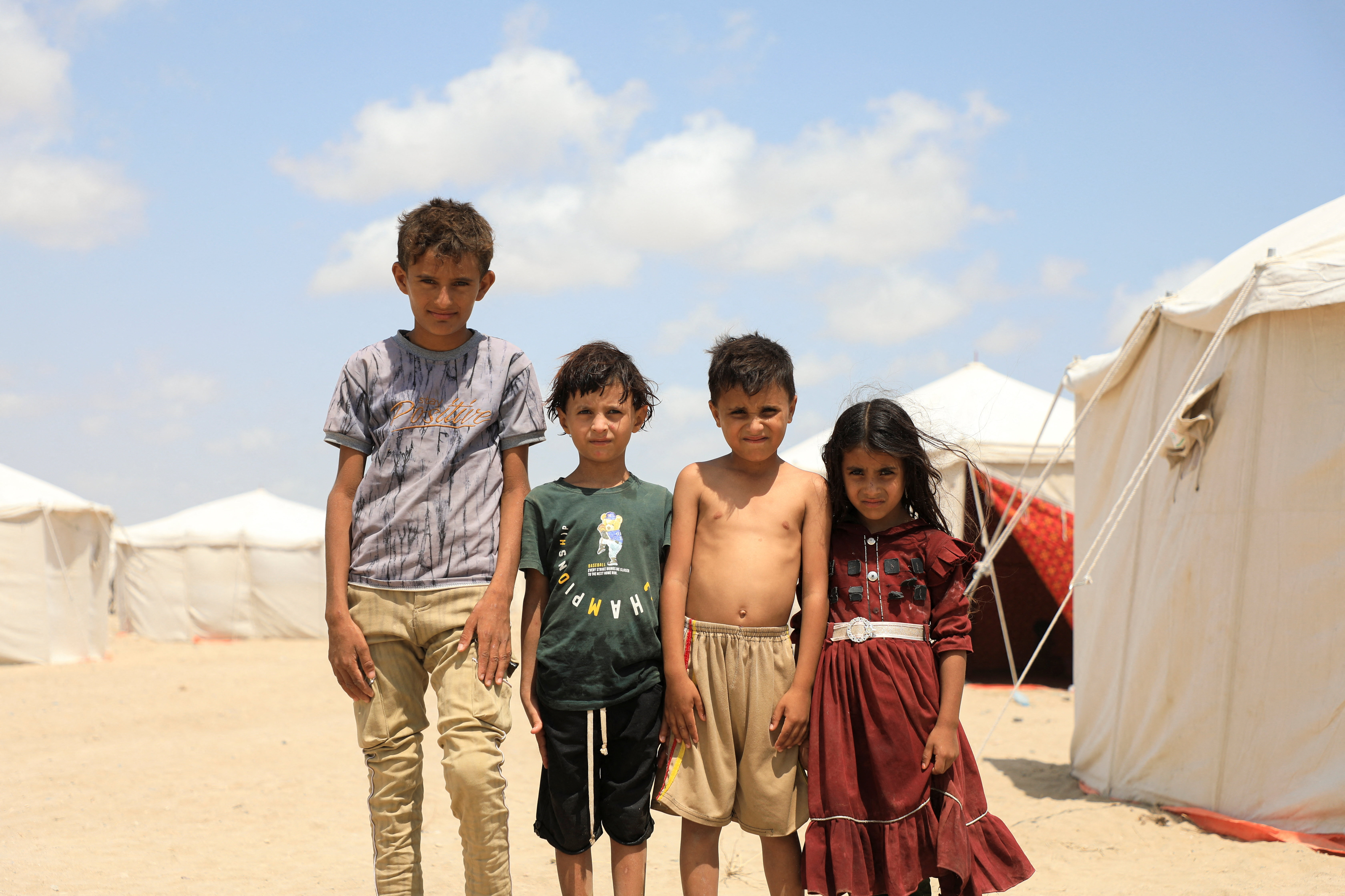 Children pause for a photo in a makeshift camp for people displaced by clashes between Iran-aligned Houthi fighters and Saudi-backed Yemeni government forces, near Aden, Yemen October 7, 2026. REUTERS/Stringer TPX IMAGES OF THE DAY